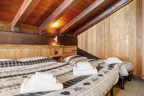three beds in a room with wooden walls at Arthemisia - Rhêmes-Notre-Dame in Rhêmes-Notre-Dame