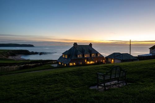 a house on a hill with the ocean in the background at Yellow Sands in Thurlestone