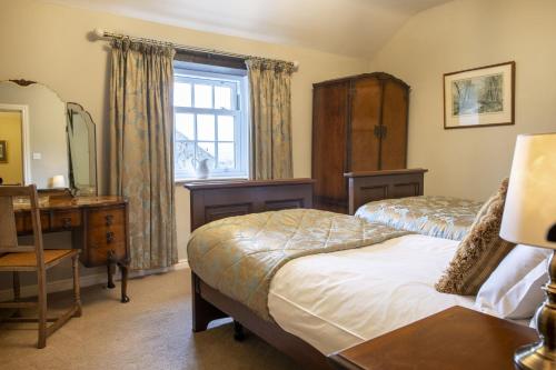 a bedroom with two beds and a desk and a window at Theaked Stones in Leyburn