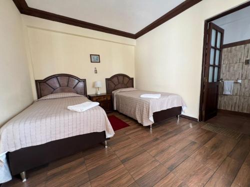 two beds in a room with wooden floors at La Culta Centro Cultural Y Hostal in Sucre