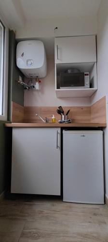 une cuisine avec des placards blancs et un comptoir avec un four micro-ondes dans l'établissement Votre Refuge Urbain Logement Complet pour Étudiants et Pros, à Rennes