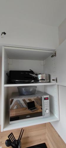 un four micro-ondes installé sur une étagère dans une cuisine dans l'établissement Votre Refuge Urbain Logement Complet pour Étudiants et Pros, à Rennes