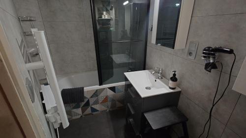 a small bathroom with a sink and a shower at Les pagotins de Garance, Chalet chaleureux Chat Gris, cosy et classé 3 étoiles in Métabief