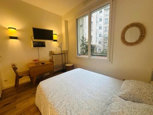 une chambre avec un lit, un bureau et une télévision dans l'établissement Studio Tour Eiffel Quai de Seine Paris, à Paris