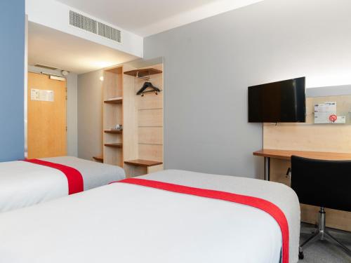 two beds in a room with a desk and a tv at Holiday Inn Express Saint-Nazaire by IHG in Saint-Nazaire