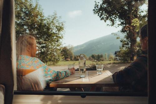 a man and woman sitting at a table with wine glasses at Thalers Mariandl in Schladming