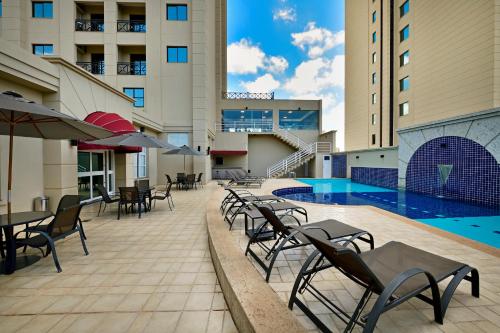 a hotel patio with tables and chairs and a swimming pool at Araucaria Plaza in Ribeirão Preto