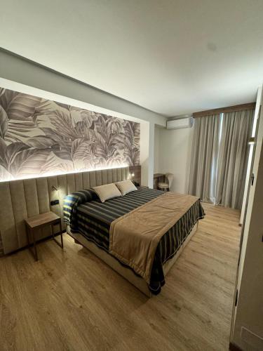 a bedroom with a large bed with a painting on the wall at Hotel Corallo in Montecatini Terme