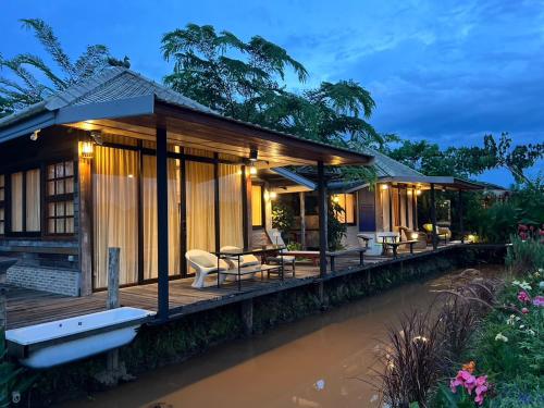 une maison avec une terrasse à côté d'une rivière dans l'établissement Khampanna Cafe' resort & Nature, à Ban Sop Nong