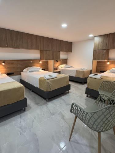 a room with three beds and a chair in it at Vida Hostel in Medellín