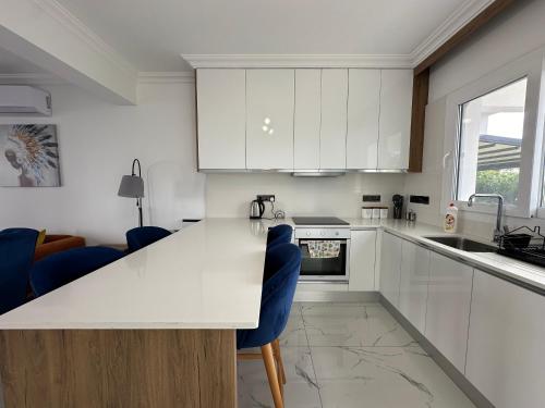 una cucina con armadi bianchi e sedie blu di Lux 1BDR Four Season a Boghaz