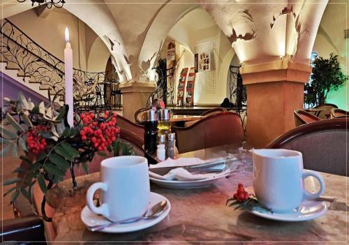 a table with two white cups and saucers on it at Hotel Restauracja Caspar in Jelenia Góra