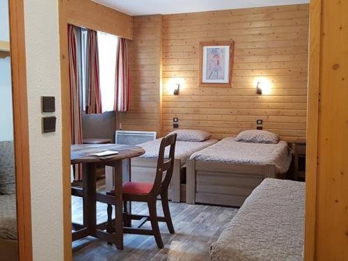 Cette chambre comprend deux lits et une table avec un bureau. dans l'établissement Studio 4 pers, balcon, parking couvert, centre Brides-les-Bains, proche thermes et télécabines - FR-1-512-237, à Brides-les-Bains