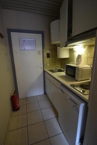 a kitchen with a white door and a microwave at Condo Gardens Leuven in Leuven