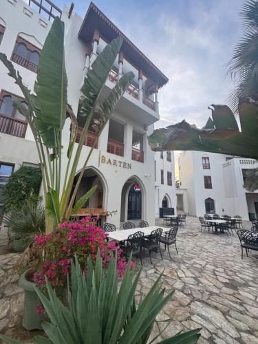 a building with a courtyard with tables and flowers at Beach house بيت البحر in As Sīfah