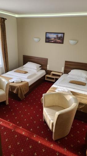 a hotel room with two beds and a chair at Vila Cristal in Baile Felix