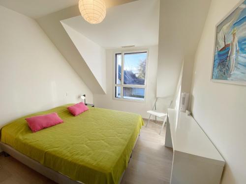 ein Schlafzimmer mit einem grünen Bett mit zwei rosa Kissen in der Unterkunft MASSALINE - Jardin clos, Plage 1km - K38 in Carnac