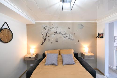 a bedroom with a bed and a clock on the wall at La P'tite Escapade - à 25 min de Caen in Creully