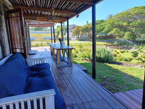 a porch with a couch and a table at The Jbaynian Guesthouse in Jeffreys Bay