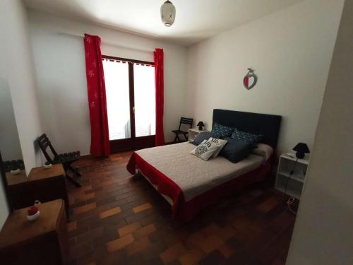 une chambre avec un lit et une fenêtre avec des rideaux rouges dans l'établissement Villa Pezza Cardo, proche centre de Porto Vecchio, à Porto-Vecchio