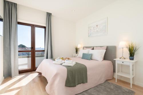 a white bedroom with a bed and a window at Bright & Spacious Retreat with Balcony by HostWise in Porto