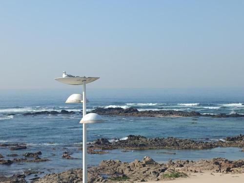 an umbrella on the beach near the ocean at Cachinnans Hostel & Apartments in Vila do Conde