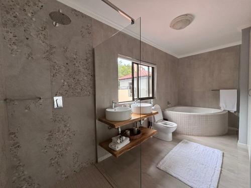 a bathroom with a tub and a sink and a toilet at Khenjadji at Fish Eagle Bay in Warmbaths