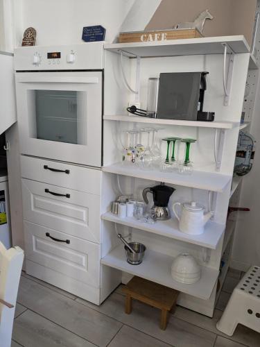 une cuisine avec des étagères blanches et un four micro-ondes dans l'établissement T2 Au pied du château sans vis à vis, à Saumur