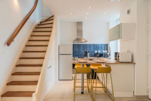 a staircase leading up to a kitchen with yellow bar stools at Maison 2 chambres avec petite cour, proche métro in Lille