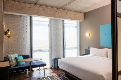 a bedroom with a bed and a table and a window at Aloft Guadalajara Sur in Guadalajara