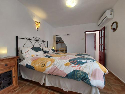ein Schlafzimmer mit einem Bett mit einer bunten Bettdecke in der Unterkunft Casa Almachar in Cómpeta
