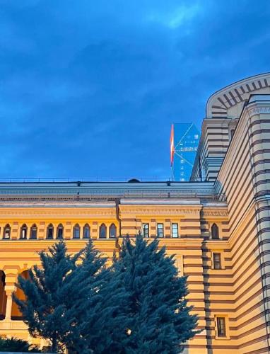 a yellow building with a flag on top of it at Opera Boutique Hotel in Tbilisi City