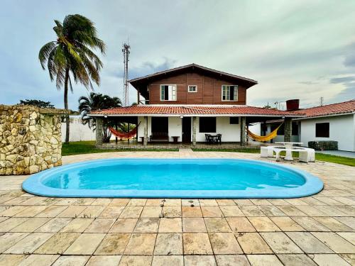 a large blue swimming pool in front of a house at Casa Bela Araçagy, 400m da praia. in São-José-do-Ribamar