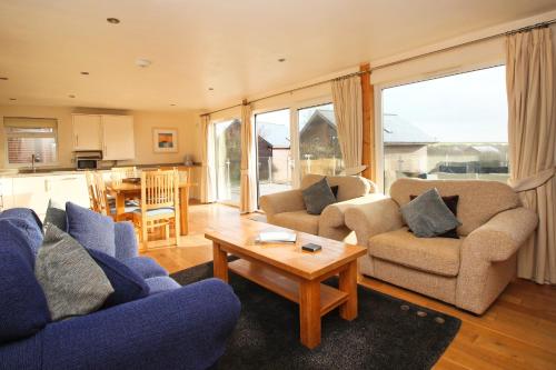 a living room with blue couches and a table at ON-SITE WATERSPORTS family lodge in Saint Columb Major