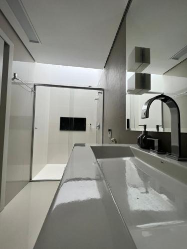 a white bathroom with a sink and a shower at Ziza Hospedagem in Maringá