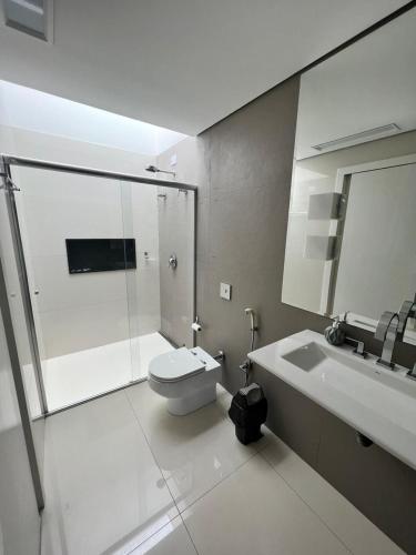 a bathroom with a shower and a toilet and a sink at Ziza Hospedagem in Maringá