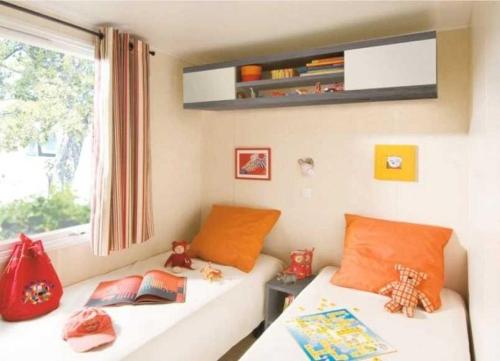 Cette chambre pour enfants comprend 2 lits et une fenêtre. dans l'établissement Camping - Parc aquatique - ccahfai, à Argelès-sur-Mer