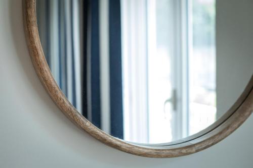 a mirror with a wooden handle on a wall with a window at Murè Hotel Numana in Numana