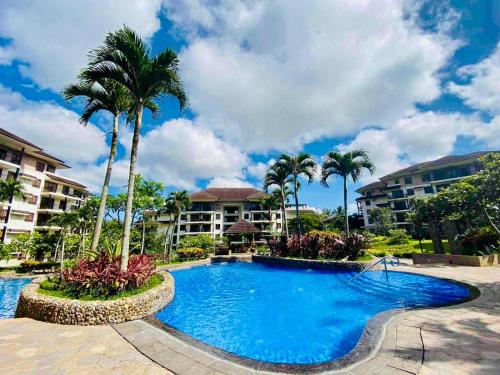 a large swimming pool with palm trees and buildings at Tagaytay Staycation - Kasa Luntian in Tagaytay