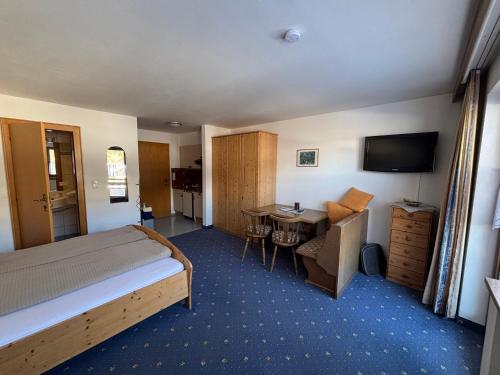 a hotel room with a bed and a desk and a television at Gästehaus Tauscher am Haldensee in Haldensee