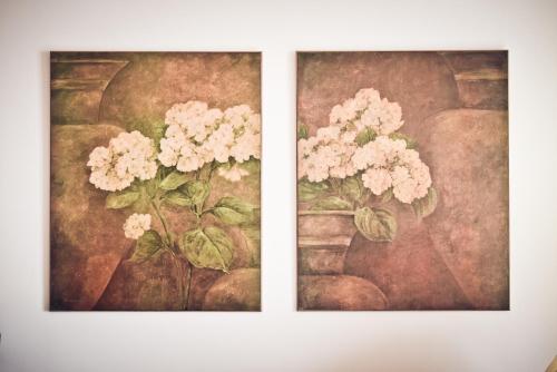 two paintings of flowers in a vase on a wall at Quinta Verde Sintra - Casa de Campo in Sintra