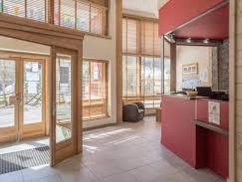 a large kitchen with red cabinets and windows in a building at Appartement Centre Skis aux Pieds, Parking & Animaux Acceptés - FR-1-513-77 in La Tania