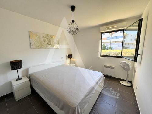 une chambre avec un lit blanc et une fenêtre dans l'établissement 3 CHAMBRES TOUT CONFORT EN BORD DE MER, à Sète