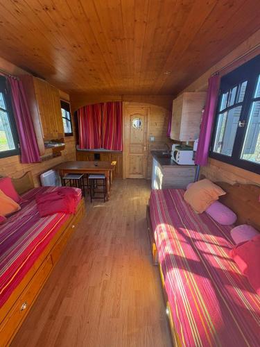 une petite chambre avec deux lits et une table dans l'établissement Roulotte a la ferme, à Pouylebon
