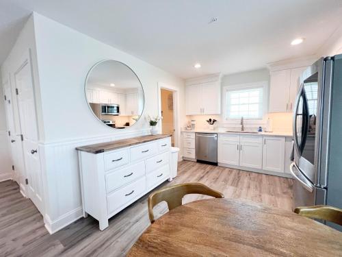 a kitchen with white cabinets and a table and a mirror at 1001 King ADA Suite, 1st Floor Serenity in Surf City