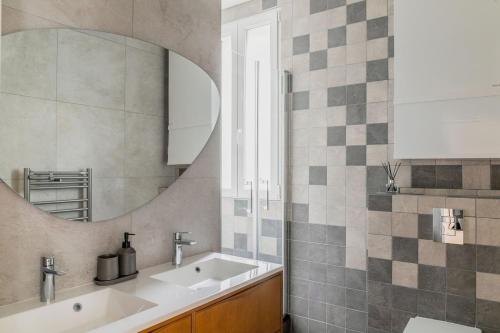 une salle de bain avec un lavabo et un miroir dans l'établissement Elegant Parisian Apartment near Eiffel Tower, à Paris