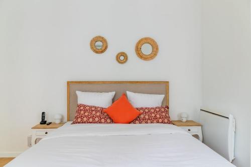 une chambre avec un lit blanc avec des oreillers orange dans l'établissement Elegant Parisian Apartment near Eiffel Tower, à Paris