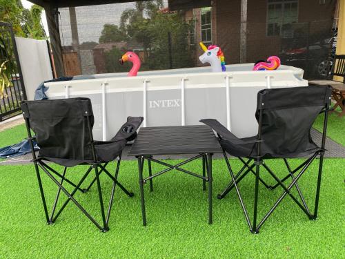 two chairs and a table with two flamingos in a yard at Rumah Puteh Mersing Kecil ROOM FULLY AIR-CONDITIONED in Mersing