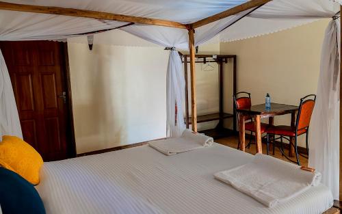 a bedroom with a canopy bed with a table and chairs at Kimberly ecolodges narok in Narok