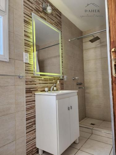 a bathroom with a white sink and a mirror at Daher Apartment Homes in La Consulta